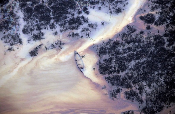 Oil flows past a sunken boat in a creek near an illegal oil refinery in Ogoniland, outside Port Harcourt, in Nigeria's Delta region, on March 24, 2011. (AP Photo/Sunday Alamba)